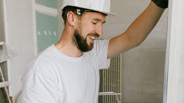 Renovation worker in white helmet drilling during interior building works